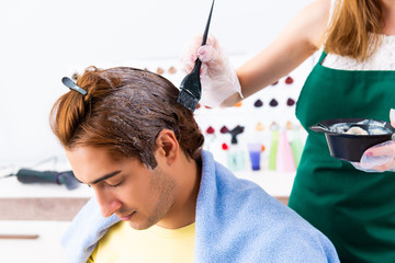 Fototapeta premium Woman hairdresser applying dye to man hair