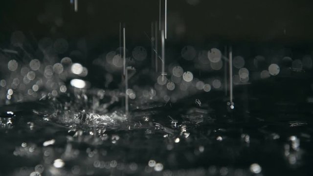 Abstract drops of rainy water covering black soil with strange spots in slo-mo  