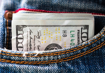 background. a pack of hundred dollar bills sticking out of a pocket of blue jeans