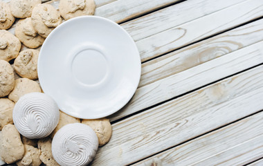 White dish, Meringue, Marshmallow, Zephyr on rustic wooden background. Flat lay. Pastry concept, copy space. Zephyr.