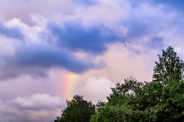 Rainbow after rain in a cloudy sky among dramatic clouds