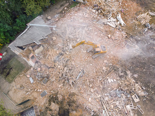 top view of demolition site. big yellow excavator clearing out site from ruins and debris