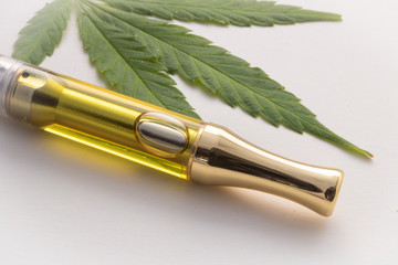 Full gram cannabis oil (THC/CBD) & terpenes in vape cartridge. Up close with weed leaf on side,