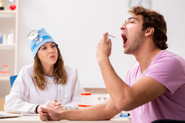 Young handsome man visiting young female doctor otolaryngologist