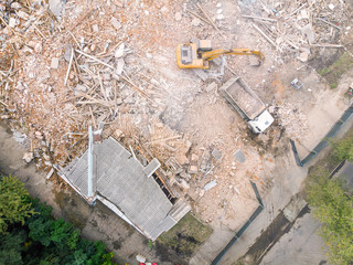aerial top view of demolition site with destroyed old building and large backhoe
