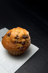 Close View of a Delicious Chocolate Chip Muffin with Grey Napkin on Dark Background