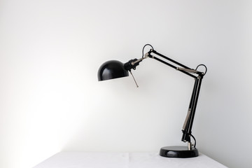 Retro black black desk lamp on white table top on white wall background with copy space product mock up placement 