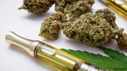 THC/CBD Concentrated Oil In Cartridge Closeup With Marijuana Herb & Glass Pipe On White