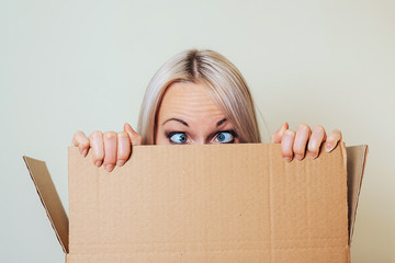 A young girl looks out of a cardboard box, depicting a goofy look with slanting eyes.