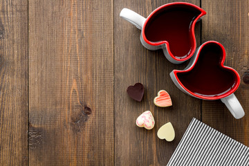 Valentine's day concept. Heart-shaped mugs and sweets on dark wooden background top view copy space