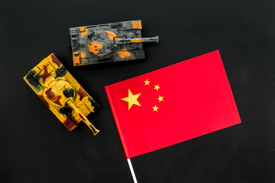 War, military threat, military power concept. China. Tanks toy near chinese flag on black background top view