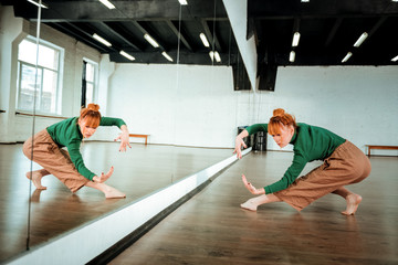 Pretty red-haired professional dancer dancing near the mirror