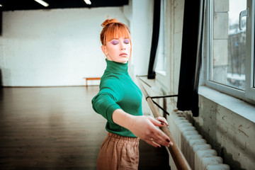 Red-haired professional ballet dancer with hair bun looking focused