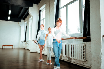 Red-haired ballet teacher and her students practicing the third ballet position