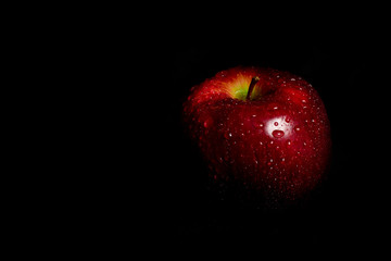full apple with water drops on black background 