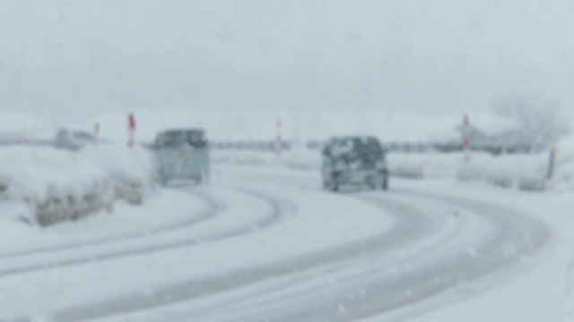 雪道を走行する自動車　大雪　冬　交通　イメージ