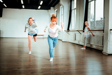 Fototapeta premium Professional ballet teacher in blue jeans and her student doing arms swings