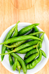 green chilies in bowl on wooden table