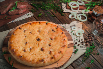 Ossetian meat pie with beef on a wooden background with ingredients. Traditional baking concept with copy space
