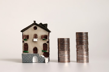 Miniature house and piles of coins.