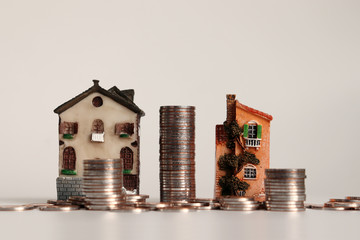 Miniature house and piles of coins.