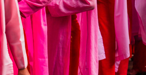 the pink, red and coral robes of young Buddhist nuns waiting in line for their last meal of the day