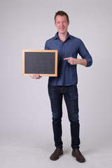 Happy young businessman holding blackboard and pointing finger