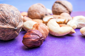 Almonds, Hazelnuts, Cashew Nuts and Whole Walnuts on Blue and Purple Background. Healthy Organic Snack, Breakfast, Food Ingredients.