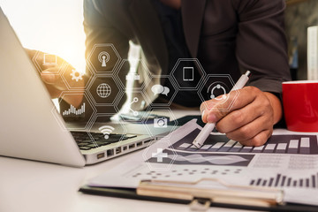 businessman or Designer using tablet with laptop and document on desk in modern office with virtual interface graphic icons network diagram.