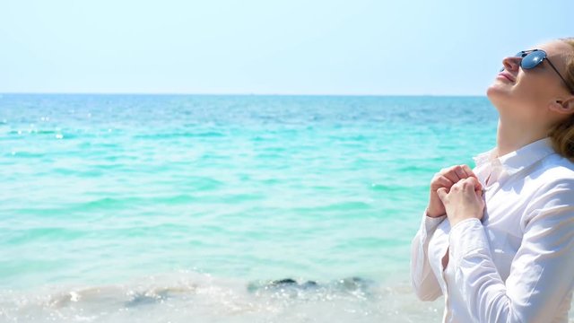 Business woman on the beach. she enjoys the view of the sea. she unbuttoned her shirt and breathes in the sea air