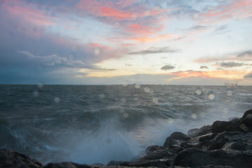 Dramatic splashing ocean wave in the evening with twilight sky in Winter at breakwater at St Kilda pier in Melbourne Australia
