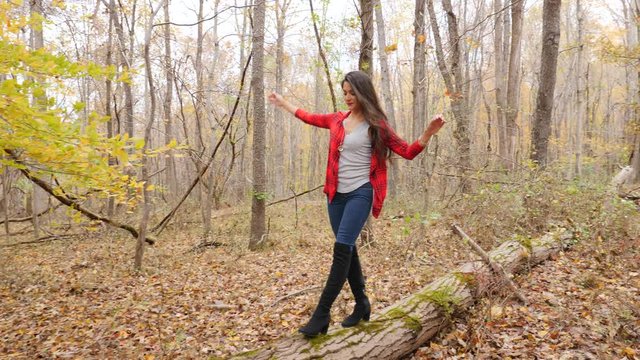 Woman walking on a log in the forest and balancing, Fall colors