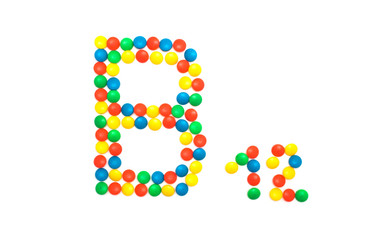 Multi-colored vitamins pills that are lined with the letter Vitamin group B12, close-up