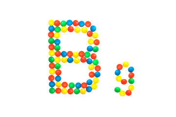 Multi-colored vitamins pills that are lined with the letter Vitamin group B9, close-up