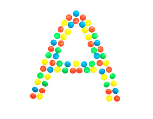 Multi-colored vitamins pills that are lined with the letter Vitamin group A, close-up