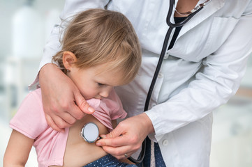 Pediatrician doctor examining a little girl by stethoscope