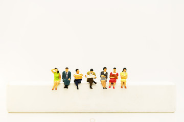 Miniature people: Business team reading book on white wooden box.