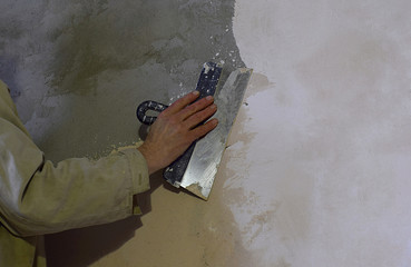 Stucco wall, hand with spatula.