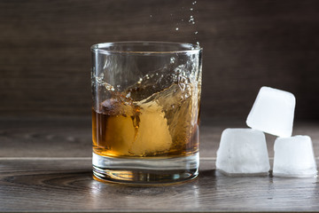 Glass of whiskey and splashing from falling ice