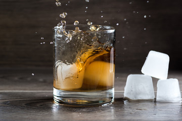 Glass of whiskey and splashing from falling ice