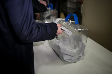 Man putting a ballot into a voting box.