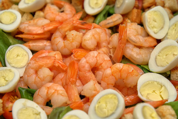 Dish with peeled shrimps, quail eggs and crackers, close-up