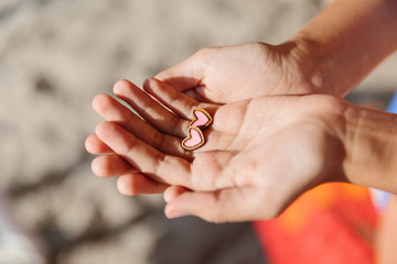 holding small wooden earrings in the shape of a heart