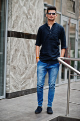 Fototapeta premium Stylish indian model man in casual clothes and sunglasses posed outdoor at street of India.
