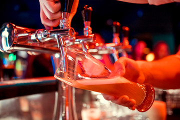 close-up of barman hand at beer tap pouring a draught lager beer