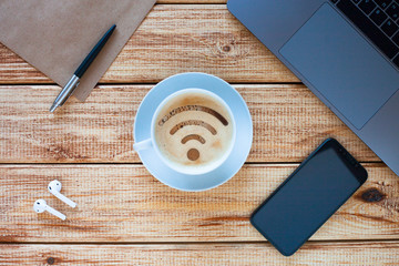 Wi-Fi business concept. Wi-Fi symbol on the cup of cappuchino with some devices support wireless connection. All set is on the light wooden background. 