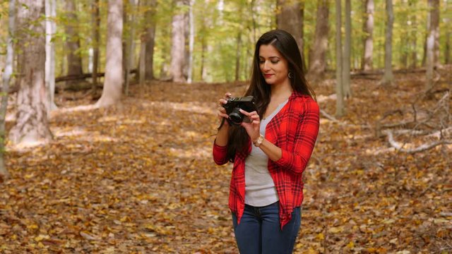 Happy female photographer in  forest taking photos of the beautiful fall colors.