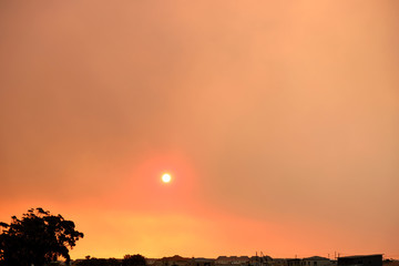Sunset while fire burns smoke-filled sky