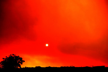 Obraz premium Sunset while fire burns smoke-filled sky