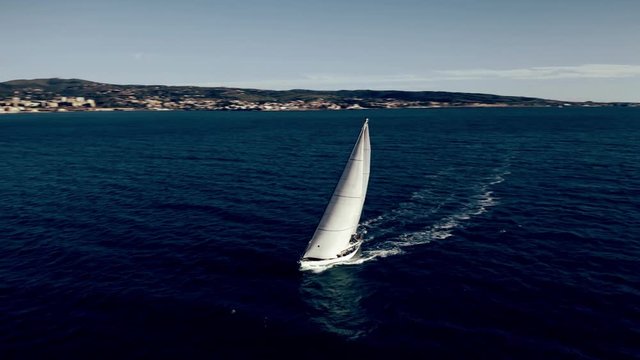 Aerial view of unknown sailboat cruising at sea